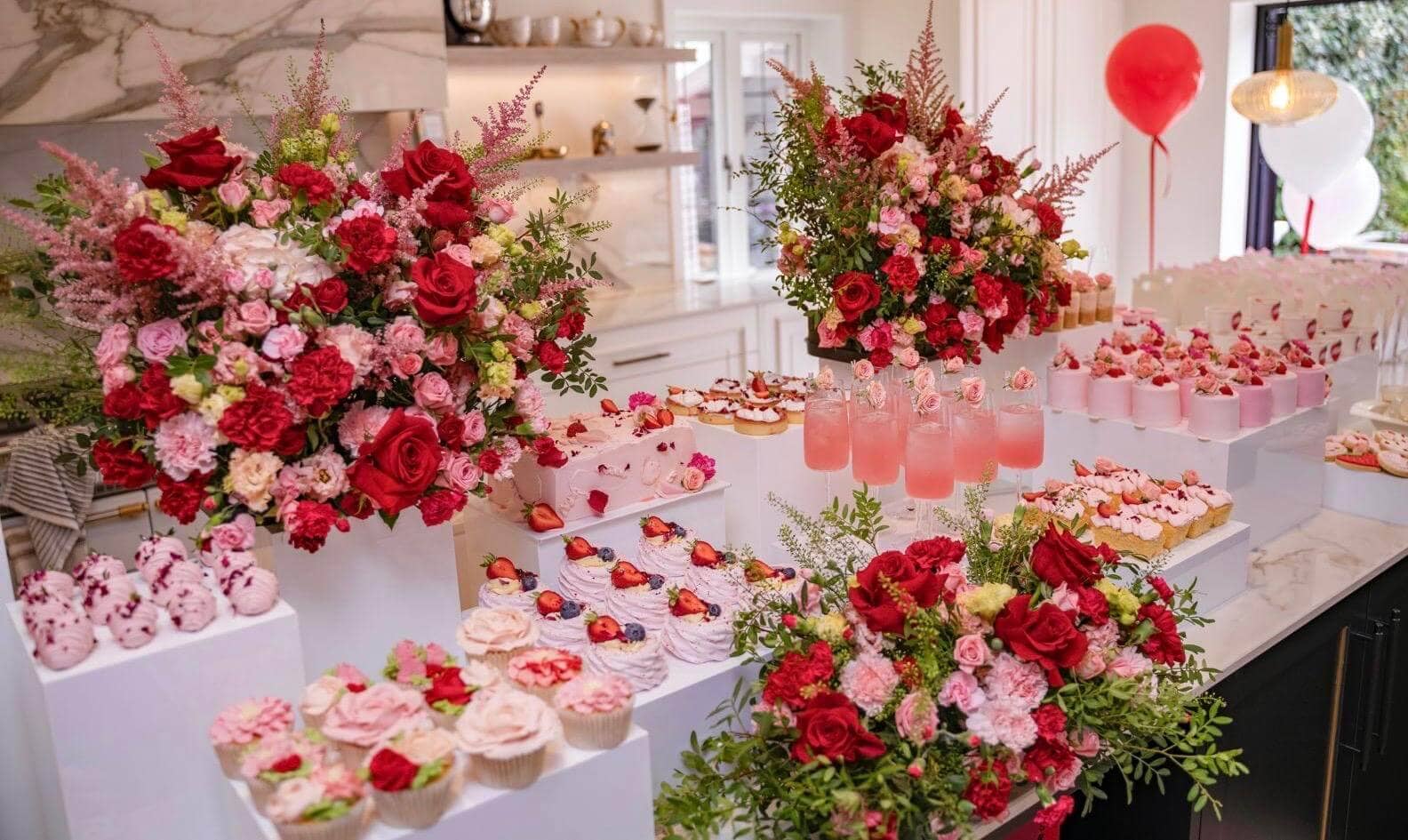 Stunning pink and red birthday dessert table with elaborate florals