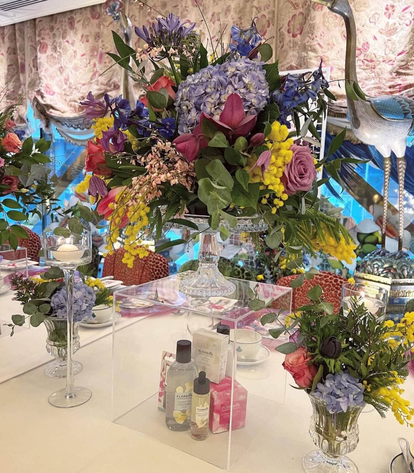 Elegant corporate event table with colorful floral centerpiece and luxury products