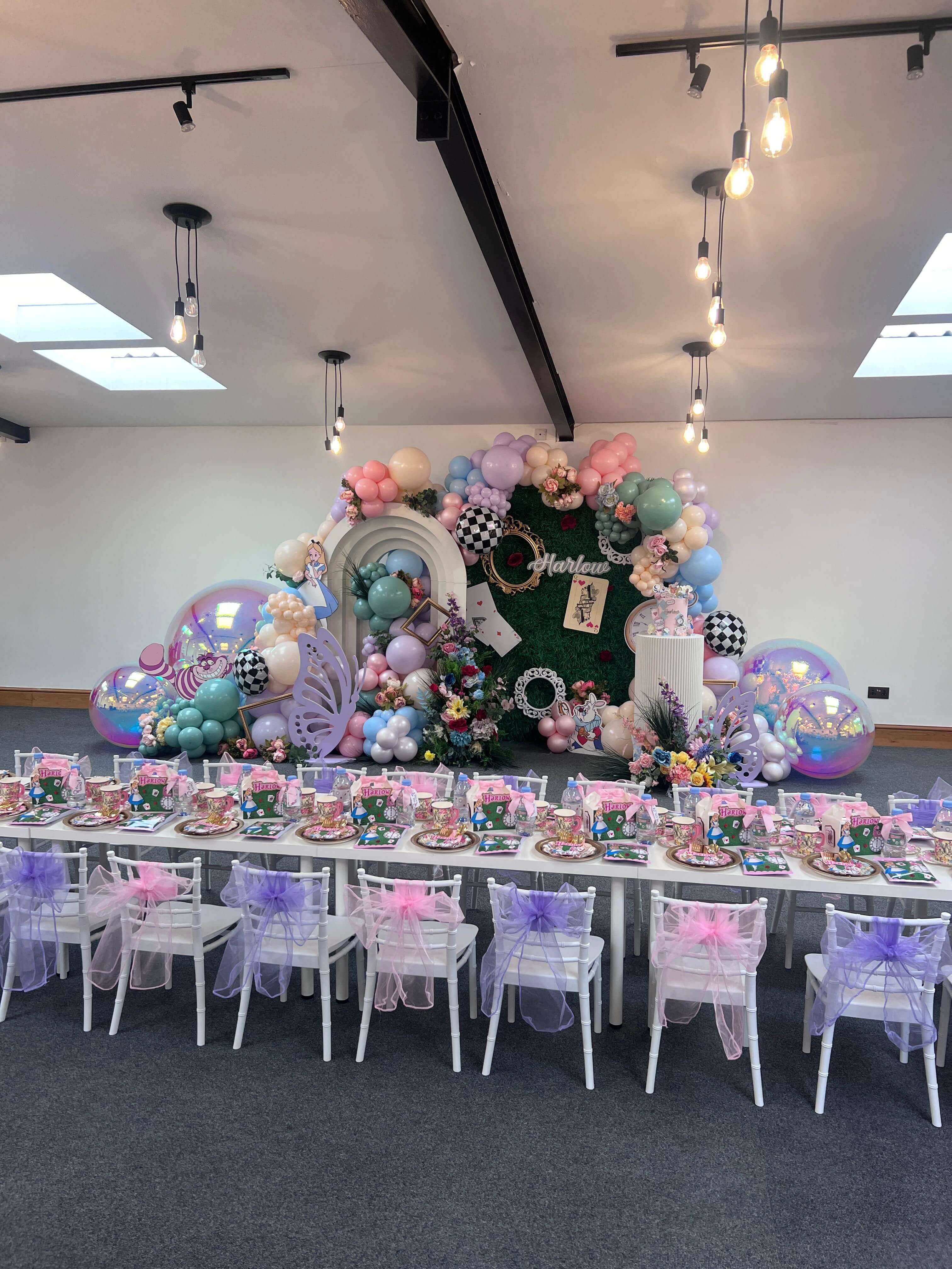 Whimsical Alice in Wonderland themed party with moss wall and pastel balloons