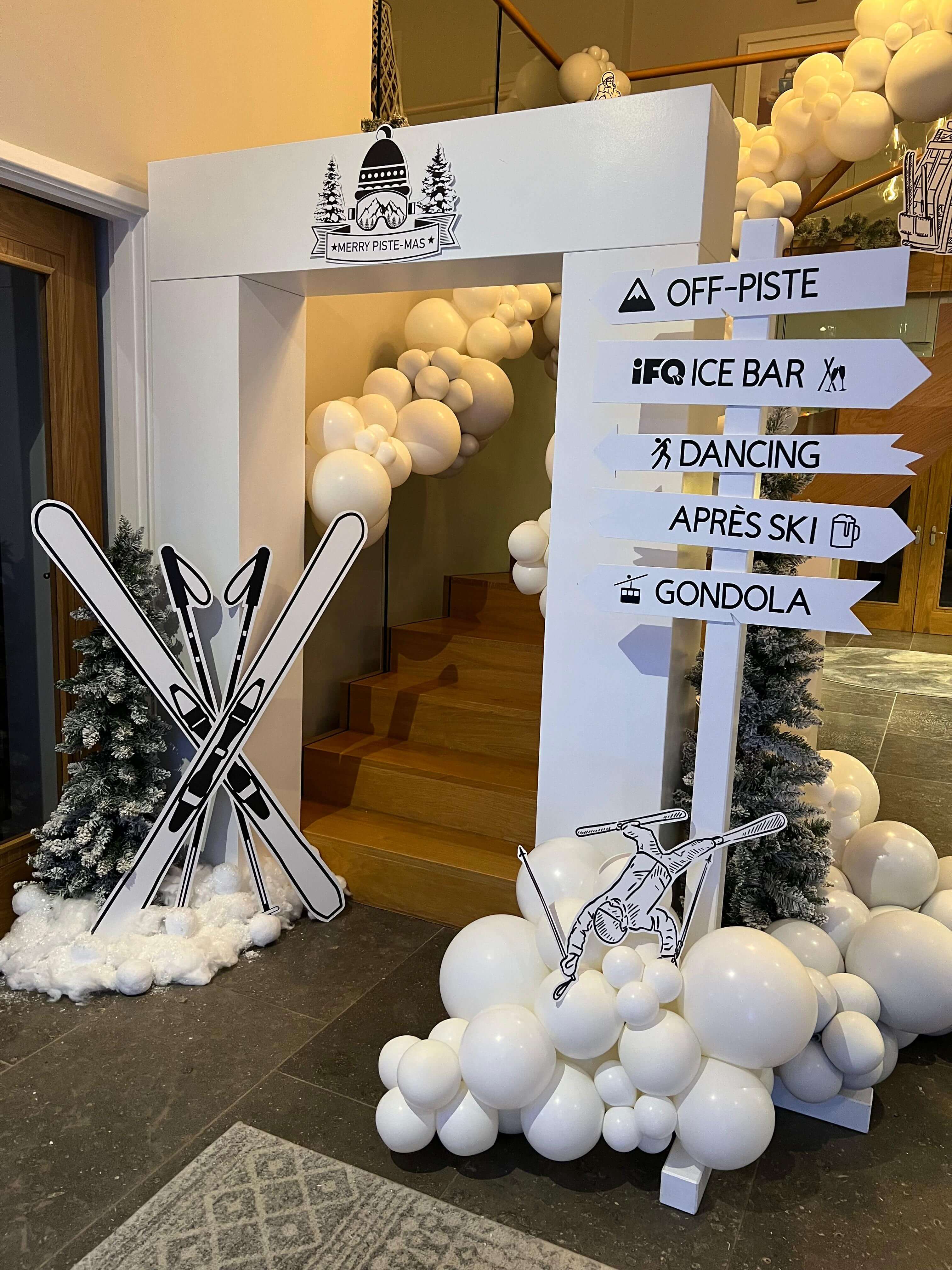 Ski resort themed entrance with directional signage and white balloon garland