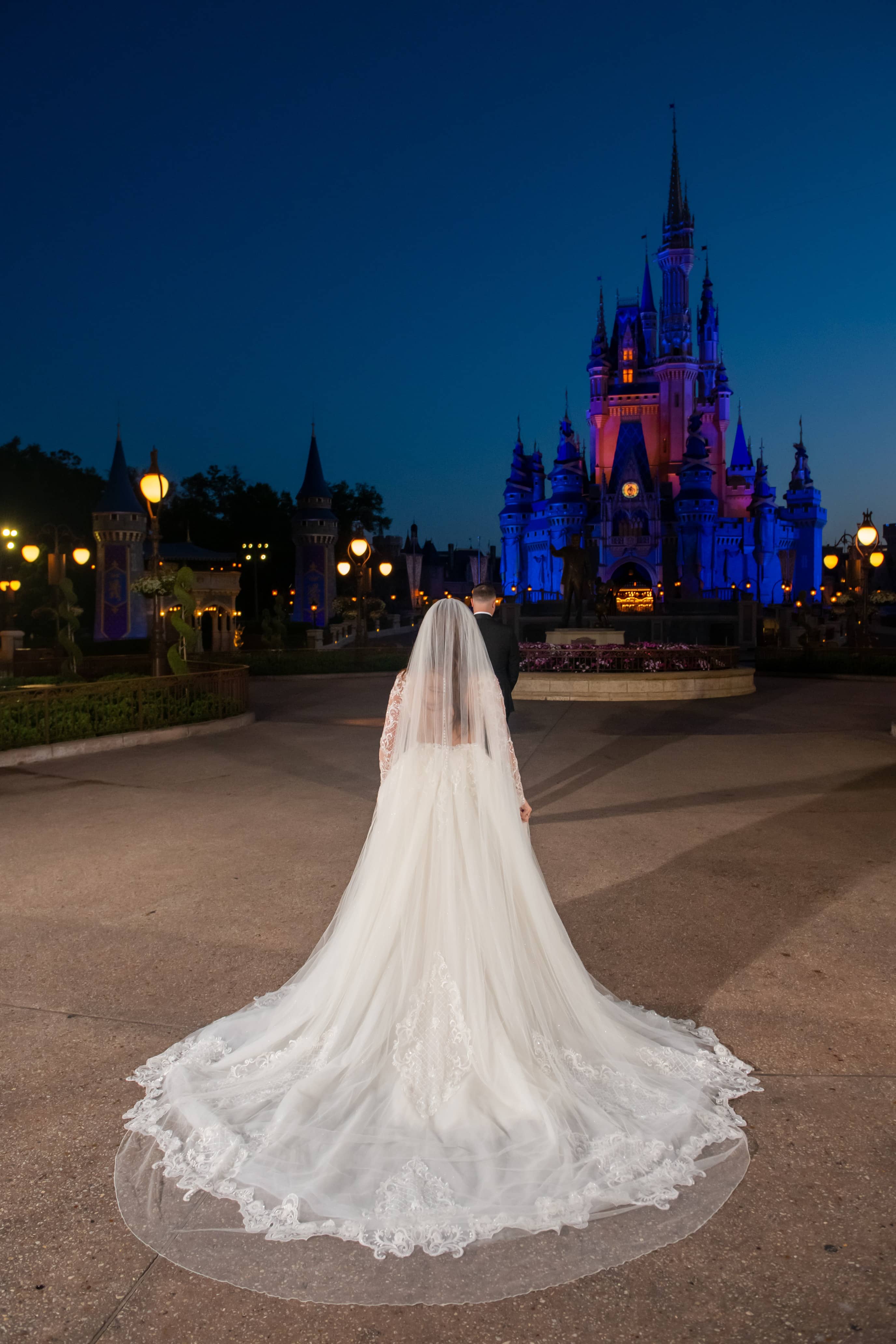 Dramatic bridal portrait at dusk with flowing veil at Disney castle with blue lighting
