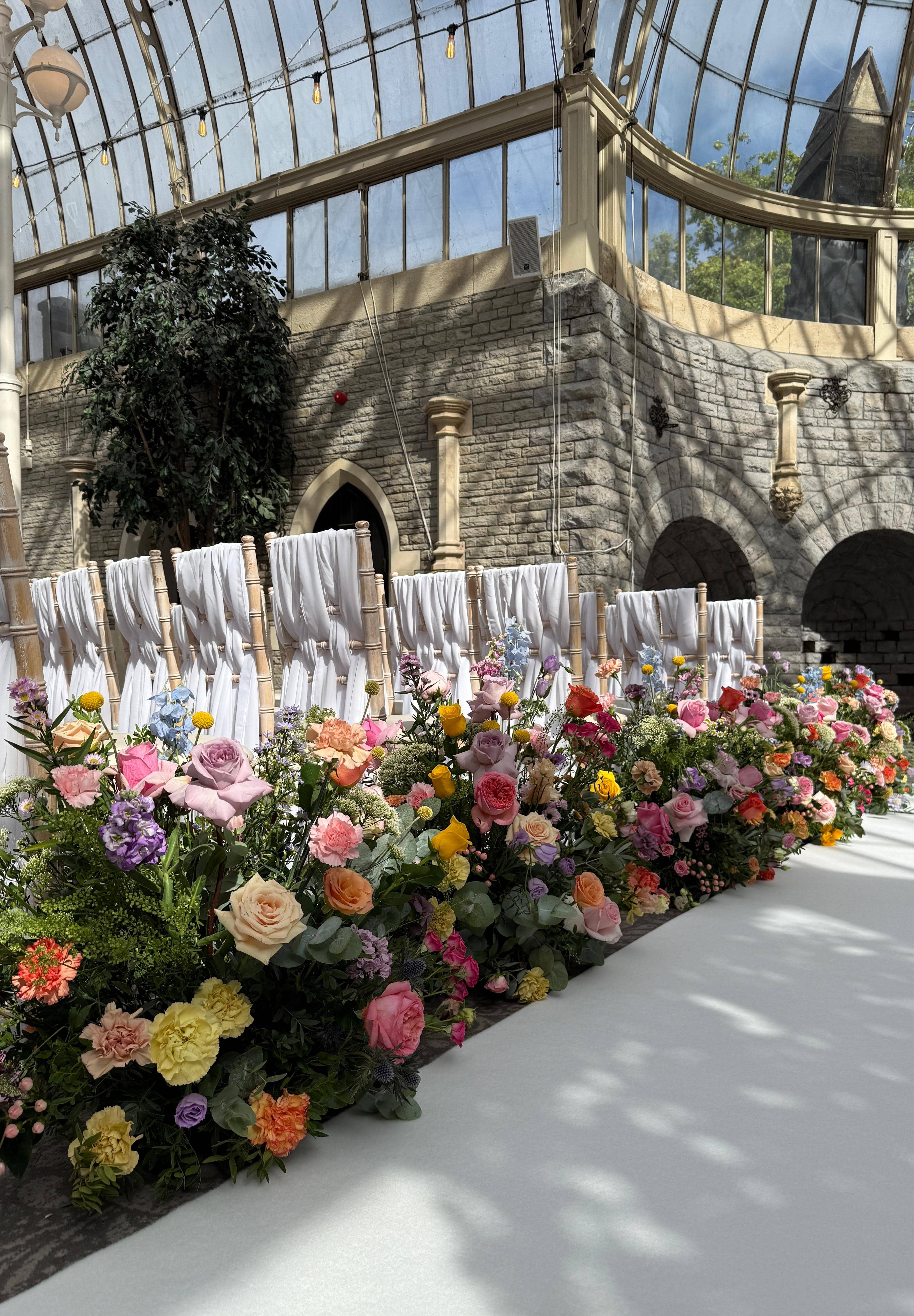 Beautiful conservatory ceremony with colorful florals lining the aisle