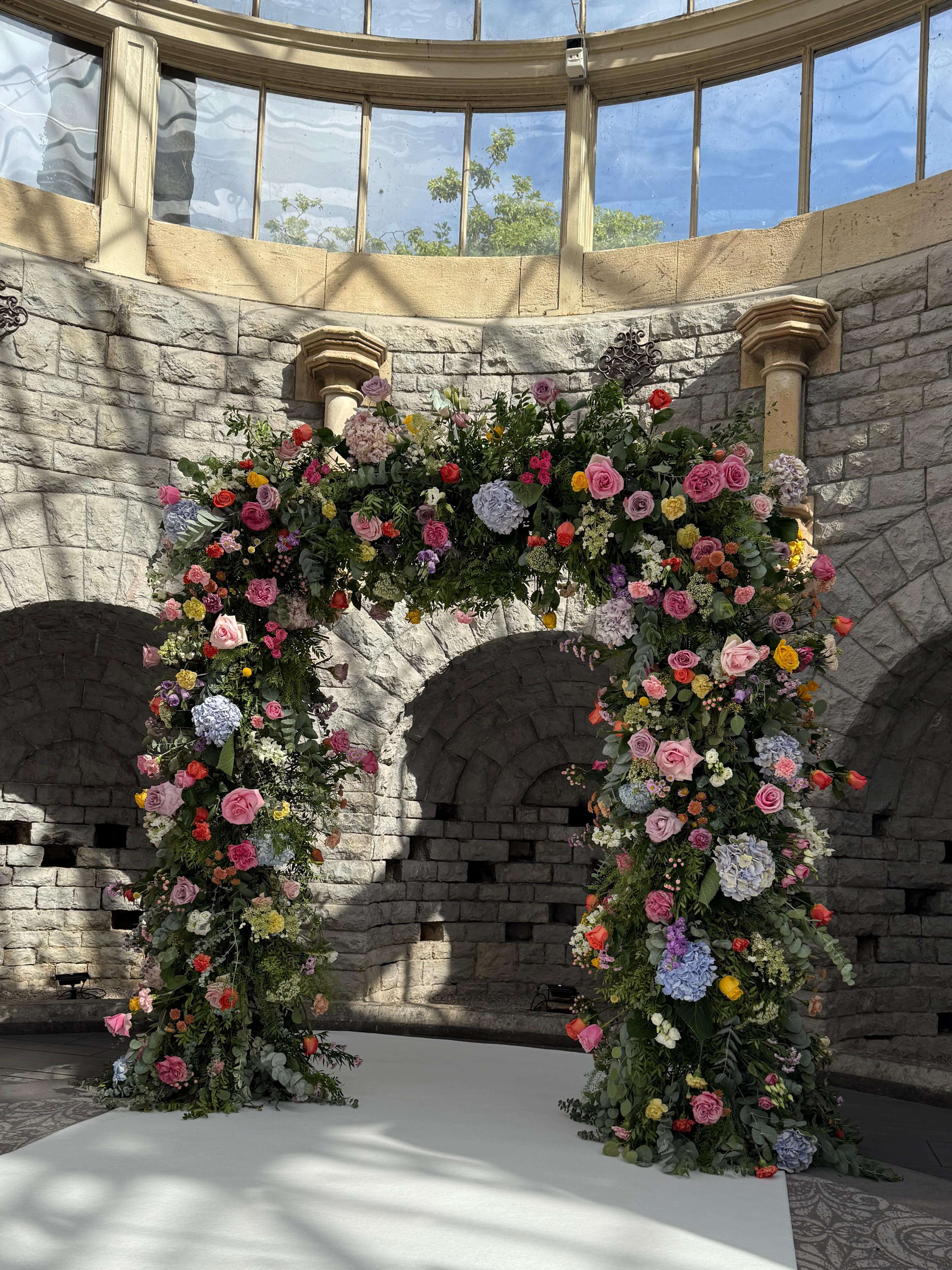 Spectacular colorful floral ceremony arch with pink, yellow, and blue blooms