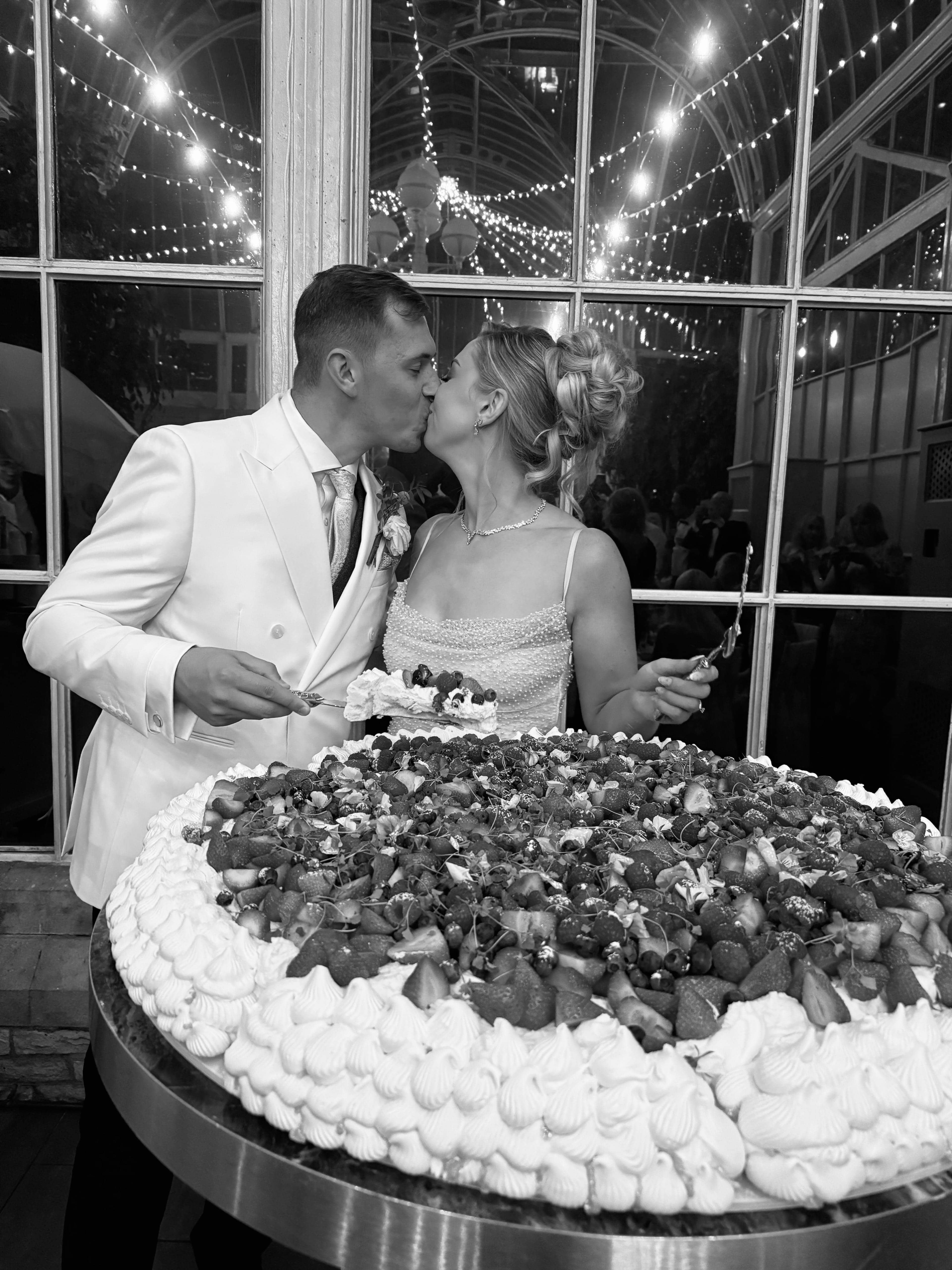 Couple celebrating over spectacular strawberry dessert cake at wedding