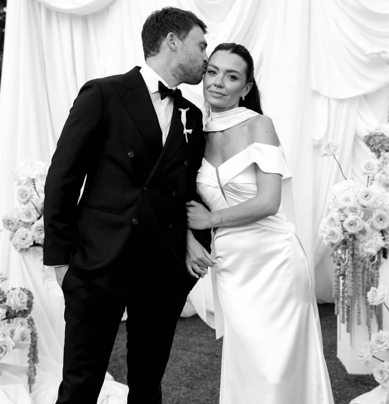 Intimate black and white wedding portrait with white rose arrangements