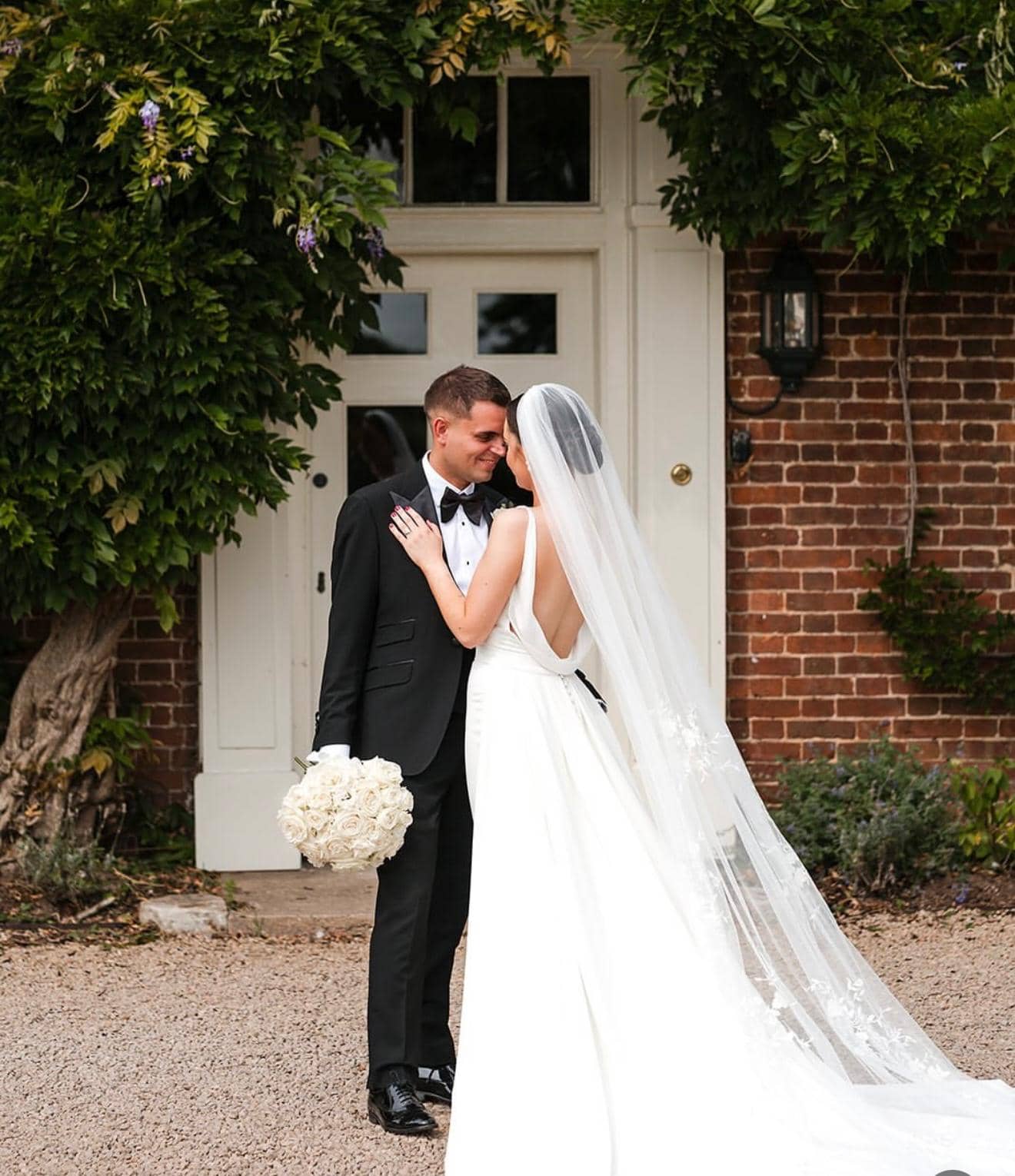 Intimate couple portrait with wisteria backdrop and white rose bouquet