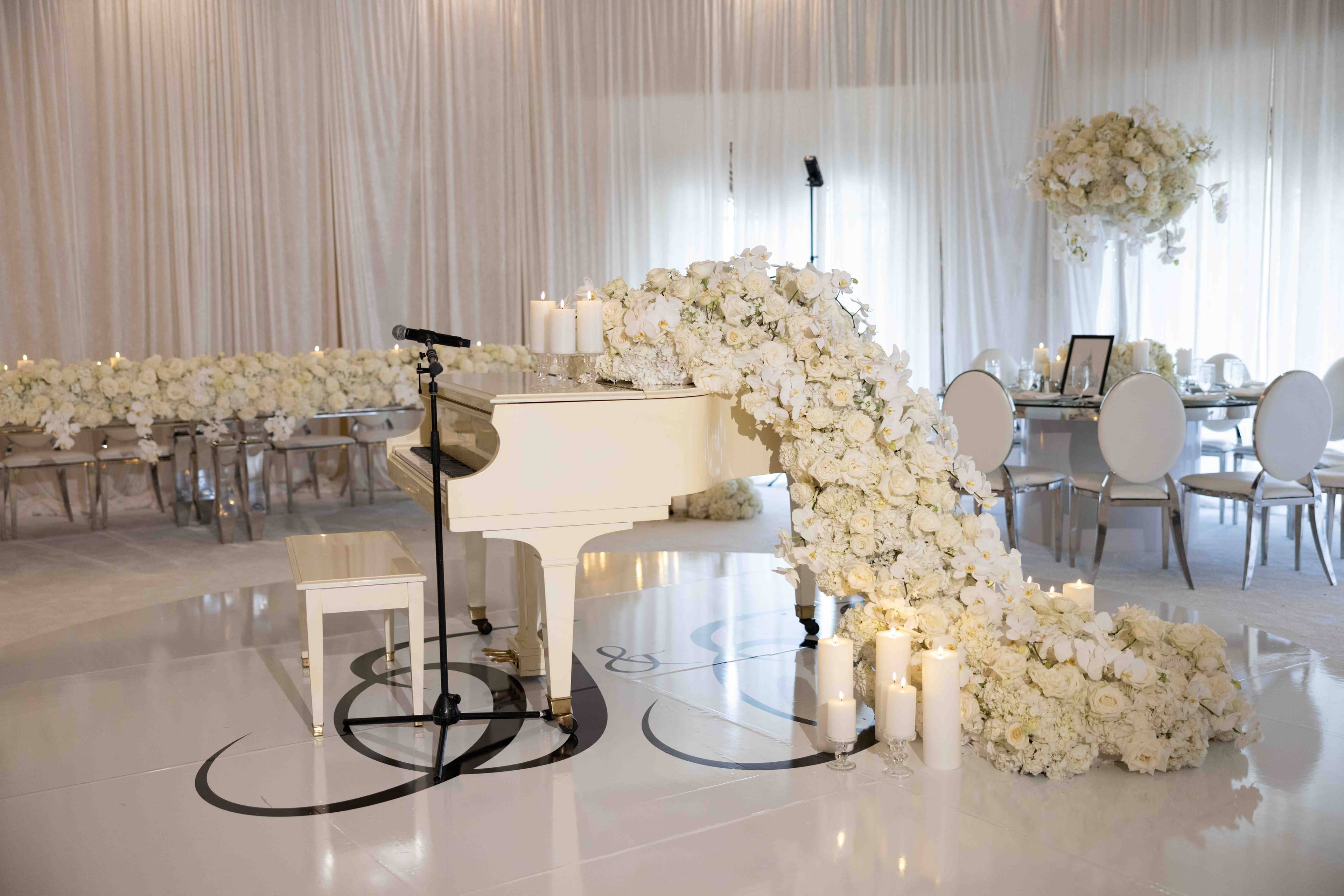 Elegant white grand piano with cascading white orchid florals at marquee wedding
