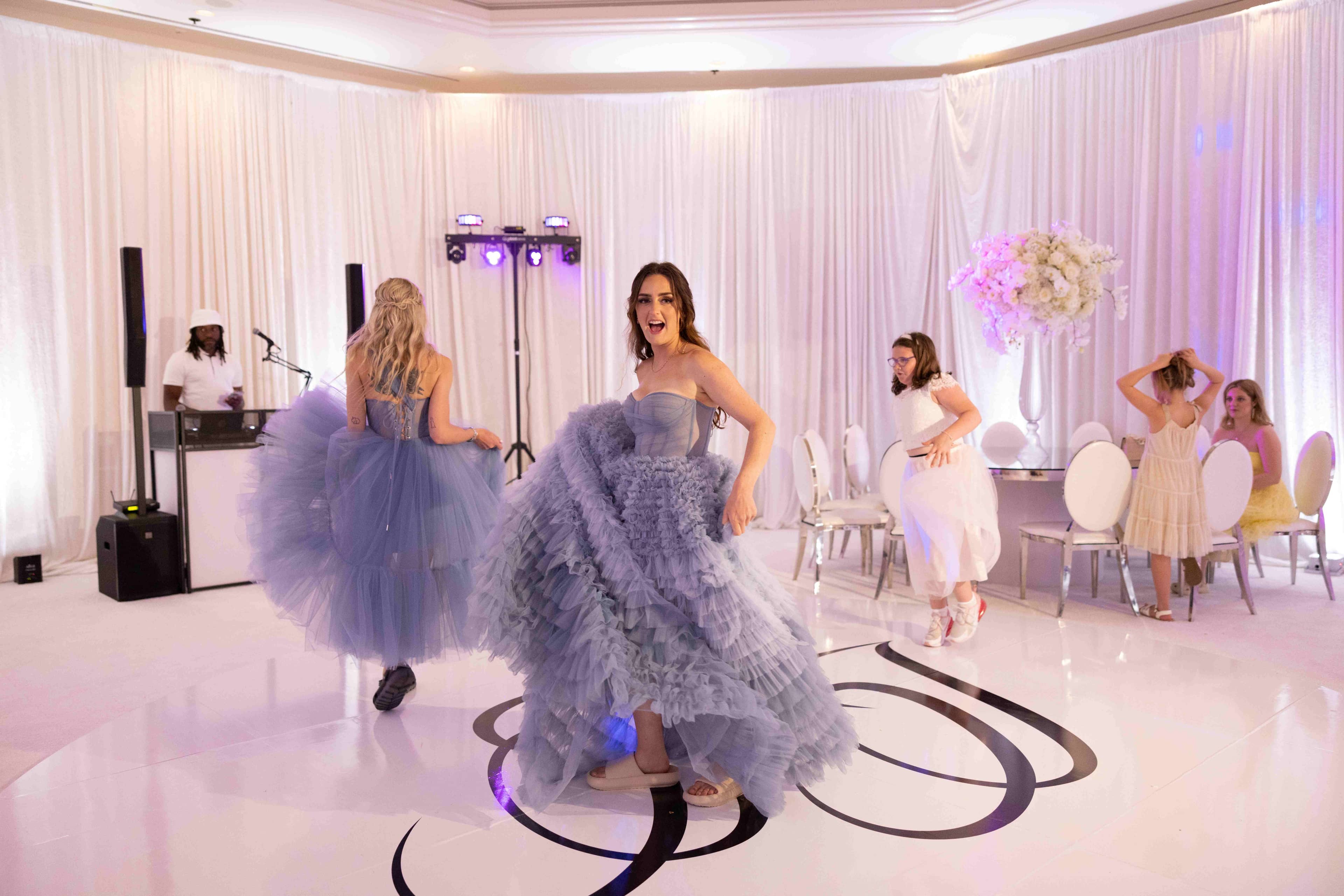 Elegant white reception ballroom with purple uplighting and monogram dance floor